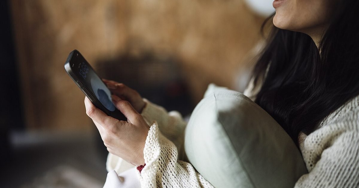 A person using a smartphone at home while checking assistant and notification settings