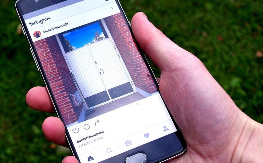 A hand holding a smartphone with a social app open, used to illustrate phone privacy choices.