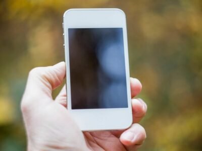 Hand holding a smartphone outdoors while preparing to take a photo