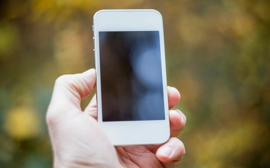 Hand holding a smartphone outdoors while preparing to take a photo
