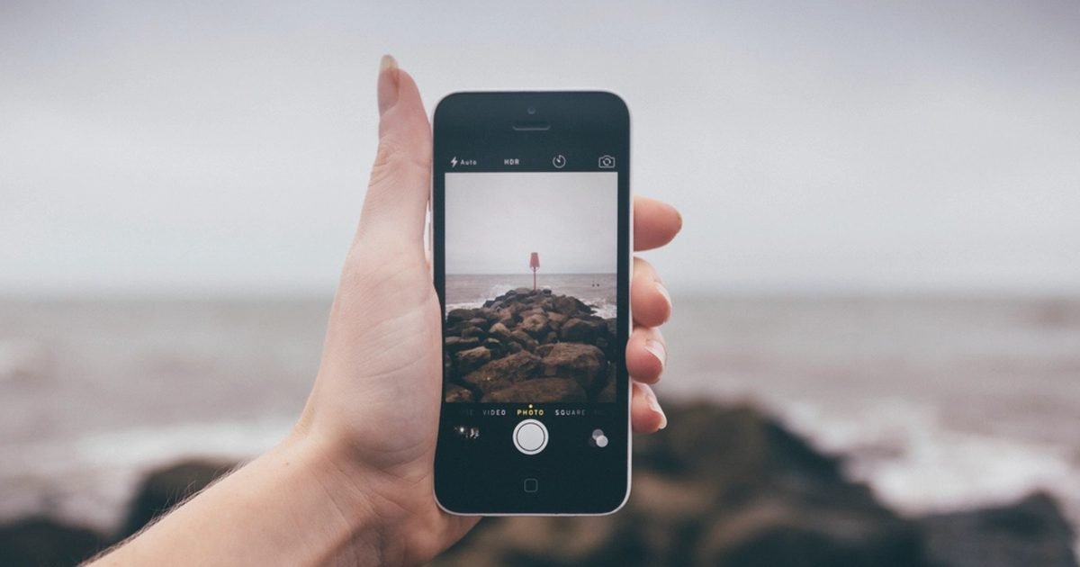 Hand holding a smartphone camera while taking a photo near the coast