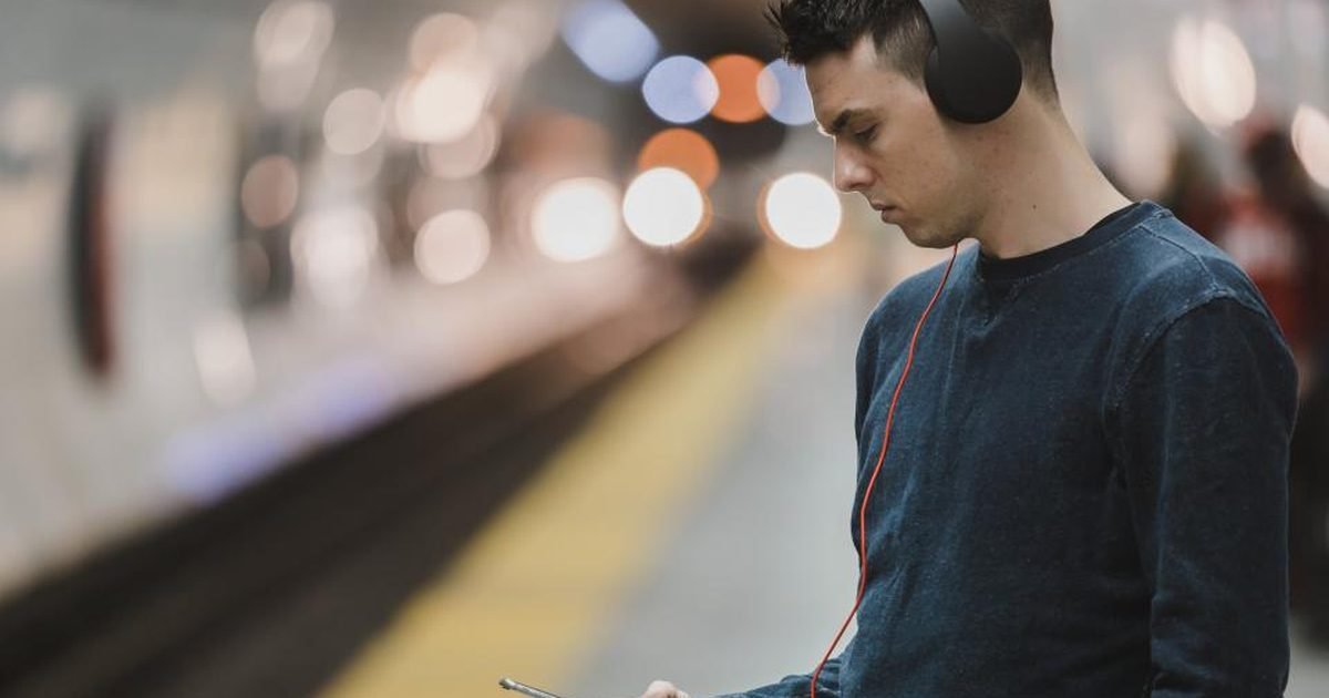 Commuter using a phone near a train platform, a common place for shoulder-surfing.
