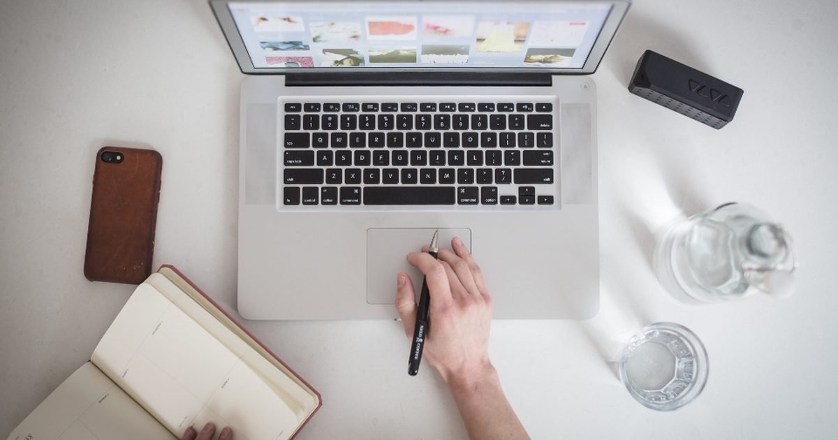 Notebook, phone and laptop on a desk for reviewing AI notes before sharing
