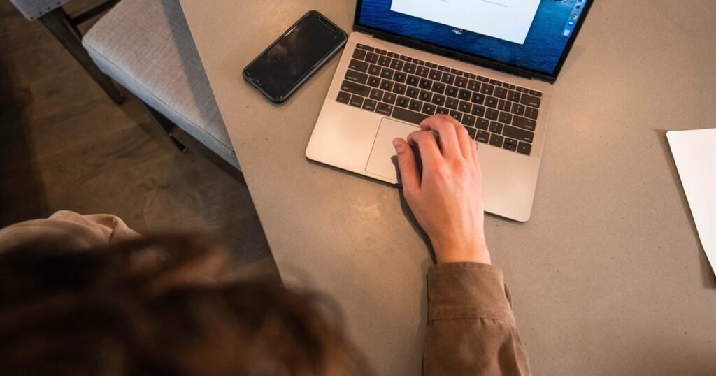 Person using a laptop with a phone nearby for private AI note taking