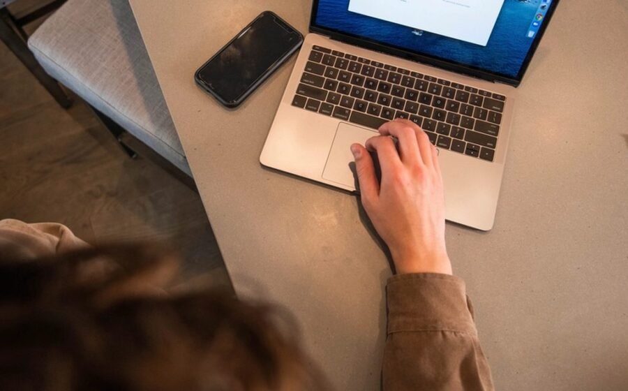 Person using a laptop with a phone nearby for private AI note taking
