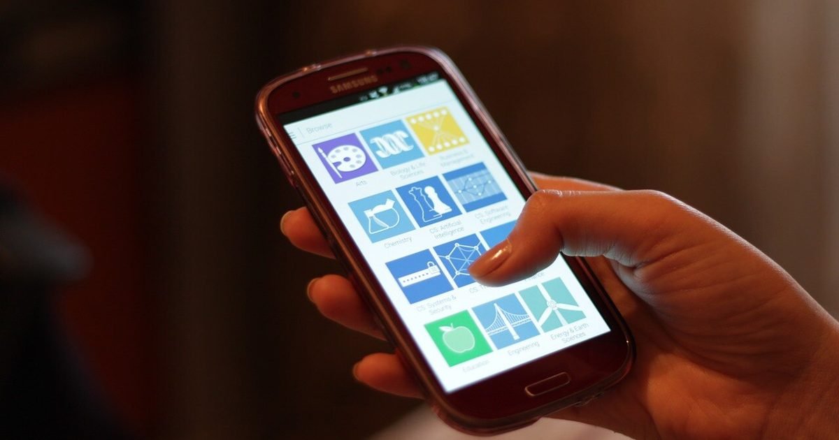 A Samsung smartphone held in hand while reviewing apps and settings