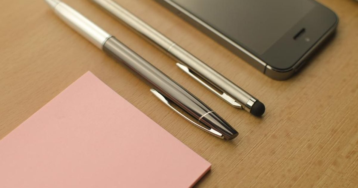 Notebook, pens and phone on a desk for organising AI study notes