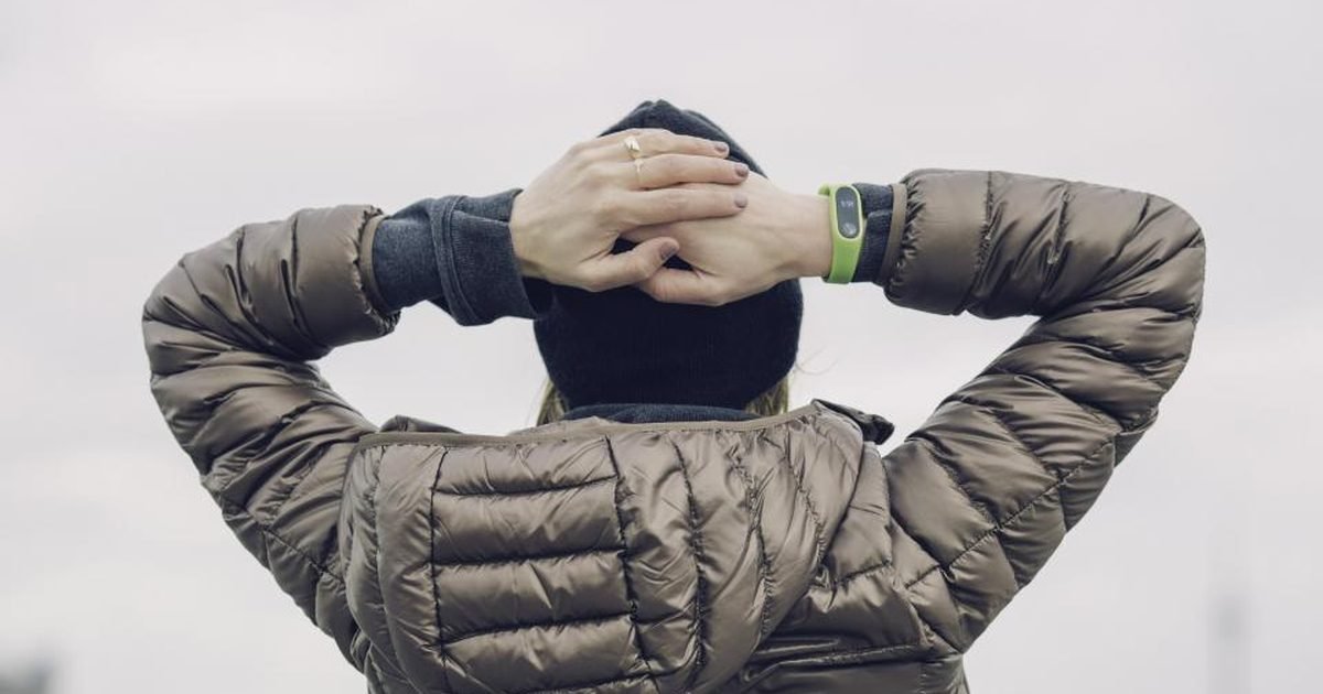 A runner stretching outdoors with a fitness tracker on one wrist