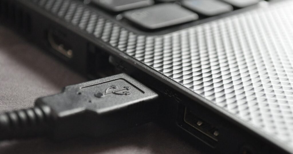 Close-up USB cable plugged into a laptop port for a USB-C hub versus dock buying guide